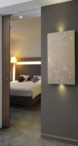 a bedroom with a bed and a painting on the wall at Novotel Avignon Centre in Avignon