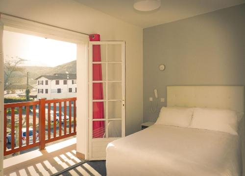 a bedroom with a bed and a balcony at Hotel Restaurant Bonnet in Saint-Pée-sur-Nivelle