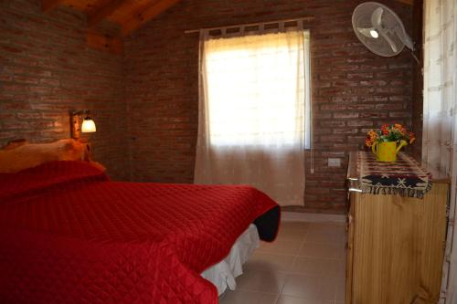 a bedroom with a red bed and a window at Der Wald cabañas in Los Reartes