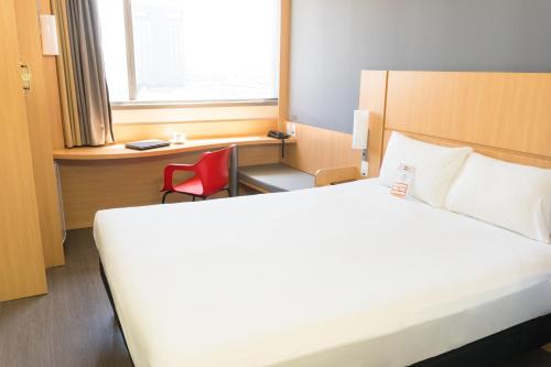a bedroom with a white bed and a red chair at ibis Rio Porto Atlantico in Rio de Janeiro