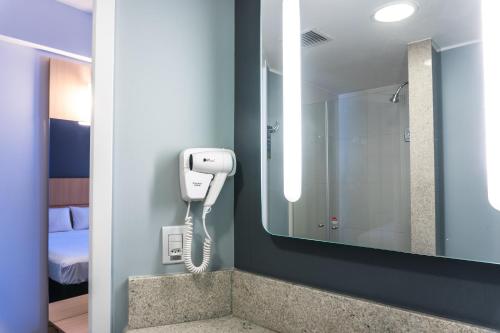 a bathroom with a phone on a wall next to a mirror at ibis Rio Porto Atlantico in Rio de Janeiro