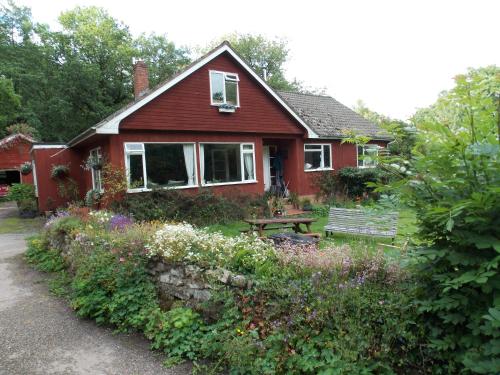 una casa roja con un banco en el patio en B&B Higher Quantock, en Stockland