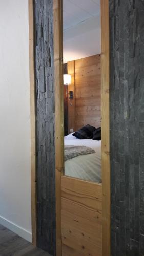 a mirror in front of a bed in a bedroom at Hôtel Du Midi in Thônes