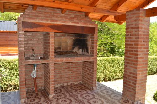 a brick fireplace in a patio with a wooden roof at Der Wald cabañas in Los Reartes