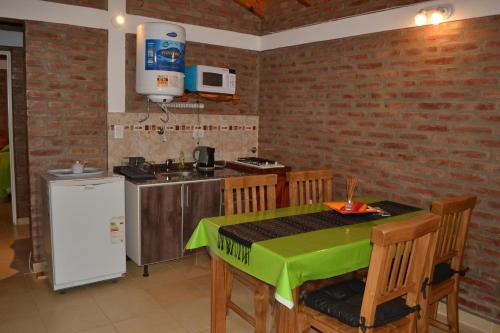 a kitchen with a green table and chairs and a refrigerator at Der Wald cabañas in Los Reartes