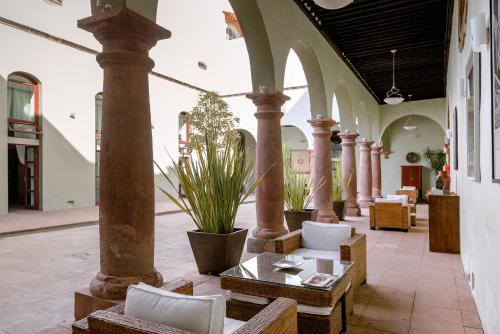 a lobby with columns and chairs and a table at Hotel La Morada in San Miguel de Allende