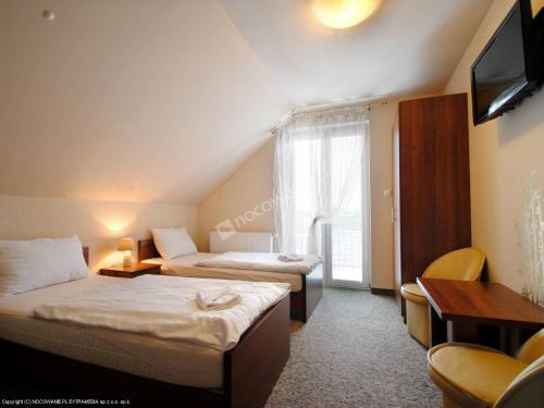 a hotel room with two beds and a television at Czar Roztocza in Zwierzyniec