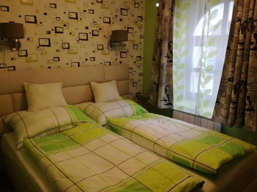 two beds sitting next to a window in a room at Fabricius apartman in Sopron