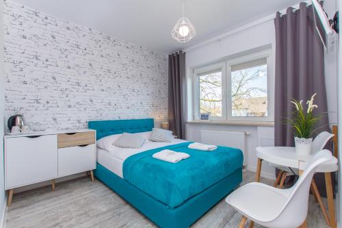 Un dormitorio con una cama azul y una pared de ladrillo blanco en Willa Riwiera, en Krynica Morska