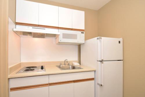 a kitchen with white cabinets and a white refrigerator at Extended Stay America Select Suites - Tampa - North Airport in Tampa