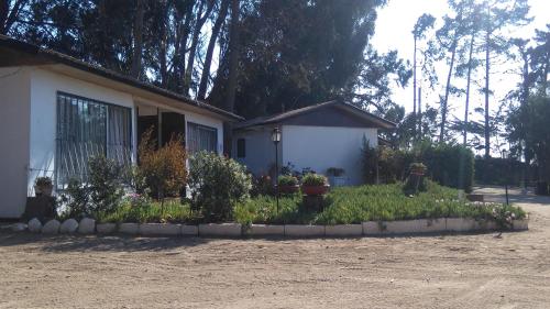 uma casa com um jardim de flores em frente em American Hotel em Los Vilos