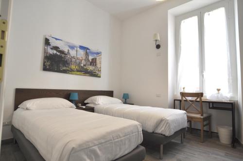 ローマにあるFlatinrome Trastevere Complexの白い壁と窓が備わる客室で、ベッド2台が備わります。