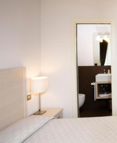a bedroom with a bed with a lamp and a sink at Il Piccolo Giardino GH ***Superior in Taormina