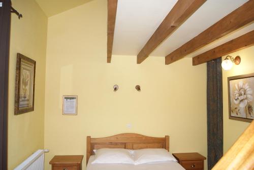 a bedroom with a wooden bed with yellow walls at Le Gîte du Tau in Touquin
