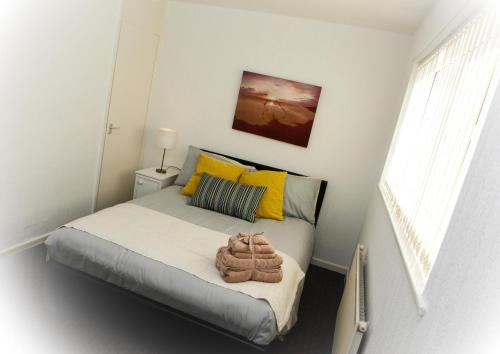 Ancoats Budget House - City Centre في مانشستر: غرفة نوم صغيرة مع سرير مع وسائد صفراء