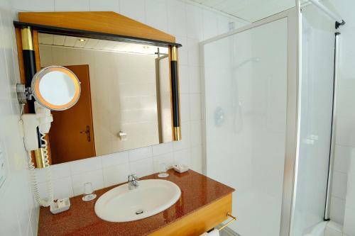 a bathroom with a sink and a mirror at Hotel-Restaurant Wanders in Elten