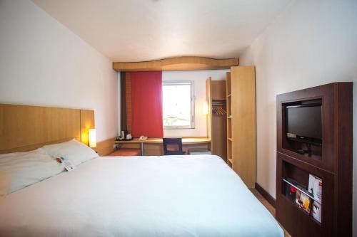 a bedroom with a white bed and a television at Ibis Lagos Airport in Ikeja