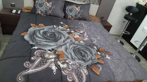 a bed with black and gray sheets and roses at Roini Apartment in Batumi