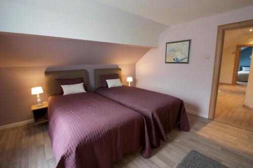 布永的住宿－La Petite Maison Maqua，一间卧室配有一张大床和紫色毯子