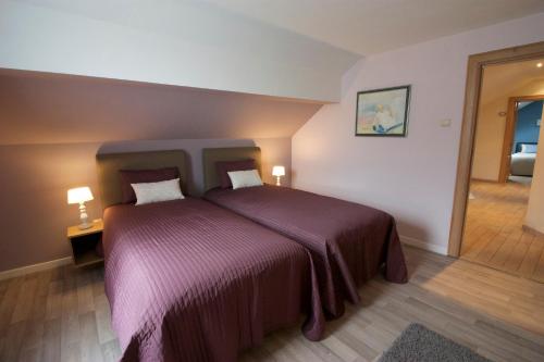 ein Schlafzimmer mit einem großen Bett mit einer lila Decke in der Unterkunft La Petite Maison Maqua in Bouillon