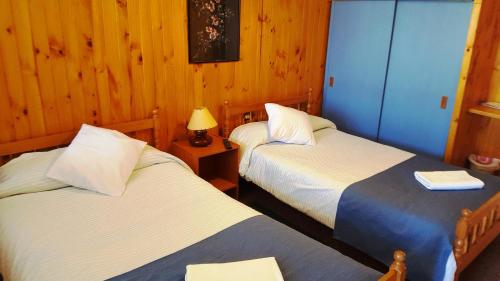 two beds in a room with wooden walls at Hostal Vista al Mar hct in Ancud
