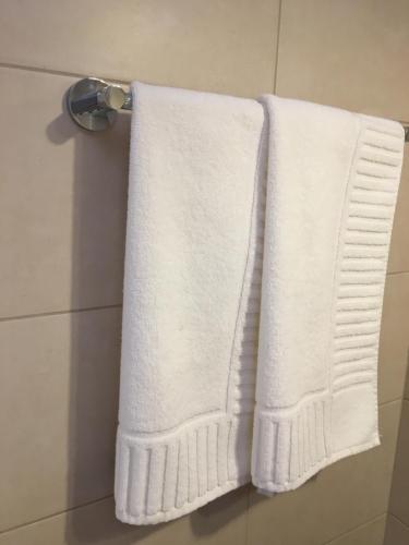un asciugamano bianco appeso a un portasciugamani in bagno di Poarta Ecaterina Residence a Braşov