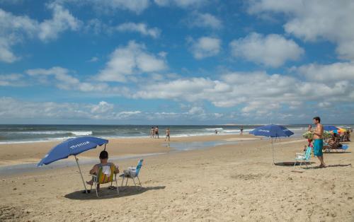 un grupo de personas sentadas en sillas bajo sombrillas en la playa en Aparts Complejo Arinos, en Aguas Dulces