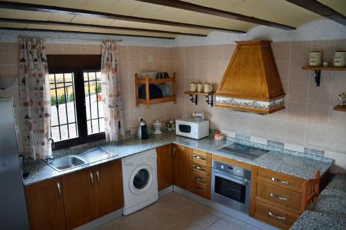 a kitchen with a sink and a washing machine at Casas Cuevas ElMirador in Fontanar