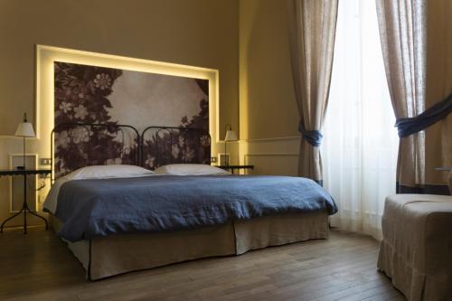 a bedroom with a bed with a painting on the wall at Locanda di Pietracupa in Tavarnelle in Val di Pesa