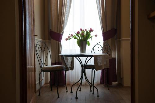 a table with a vase of flowers on it in front of a window at Locanda di Pietracupa in Tavarnelle in Val di Pesa