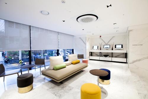 a living room with a couch and some tables and chairs at G2 Hotel Myeongdong in Seoul