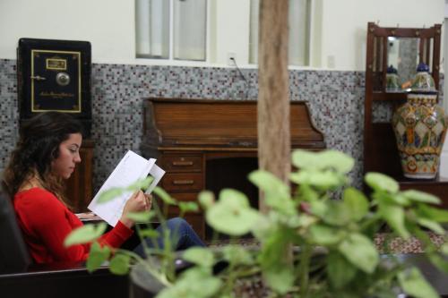 a woman reading a paper in front of a piano at Hotel de los baños in Pachuca de Soto