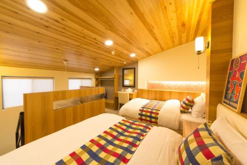 two beds in a small room with wooden ceilings at W Hostel in Tainan