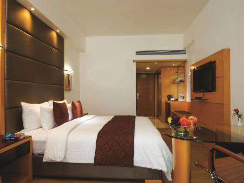 a hotel room with a bed and a television at The Central Residency in Trivandrum