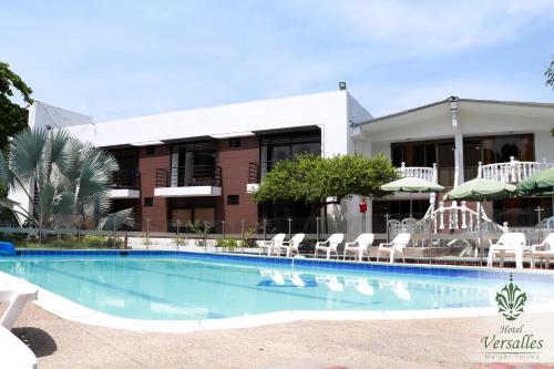 a pool with chairs and umbrellas in front of a building at Hotel Restaurante Versalles in Melgar