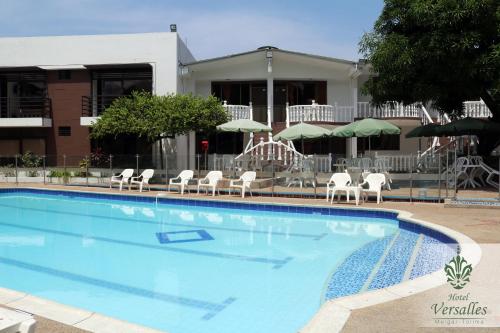 梅爾加的住宿－Hotel Restaurante Versalles，一个带白色椅子和遮阳伞的大型游泳池