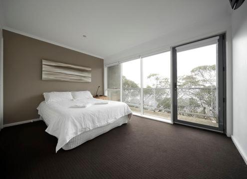 a bedroom with a white bed and a large window at Elkhorn 7 in Mount Buller