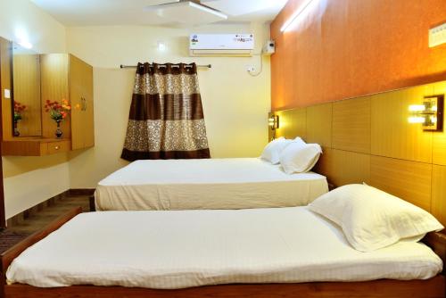 two beds in a room with a window at Hotel Ganga Tamilnadu in Nāgercoil