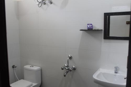 a white bathroom with a toilet and a sink at Rams Inn in Thanjāvūr