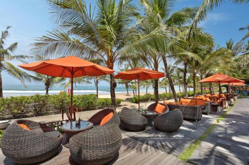 a row of tables and chairs with umbrellas on the beach at Legian Beach Hotel in Legian