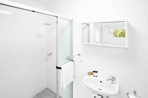a white bathroom with a sink and a shower at Aspire Newcastle in Newcastle