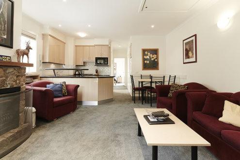 a living room with red couches and a kitchen at Reindeer 9 in Mount Buller