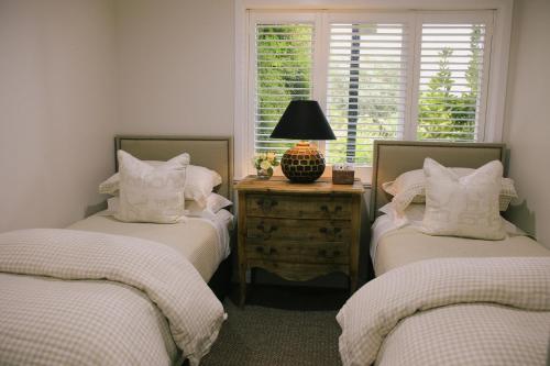 a bedroom with two twin beds and a lamp on a table at Ngamihi Lodge in Rotorua