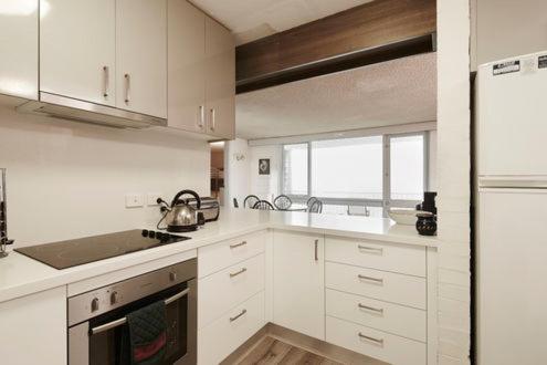 - une cuisine blanche avec évier et cuisinière dans l'établissement Twin Towers 403A, à Mount Buller