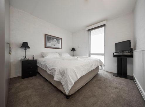 - une chambre blanche avec un lit et une télévision dans l'établissement Twin Towers 403A, à Mount Buller