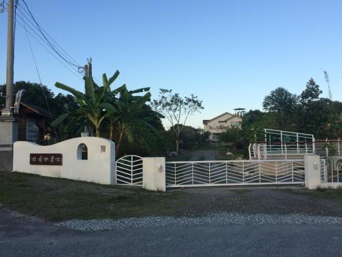 a white fence with a gate on a road at Oliver Tree B&B in Fenglin