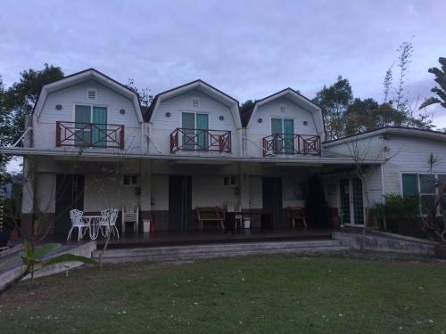 a white house with a balcony and tables and chairs at Oliver Tree B&B in Fenglin