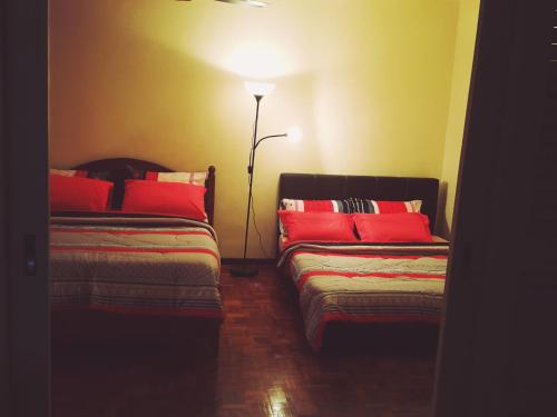a room with two beds with red pillows and a lamp at D Savoy Famosa Condo in Melaka