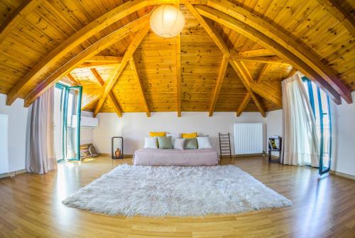 um quarto com uma cama num quarto amplo com tectos em madeira em Joya Luxury Villas em Kypseli