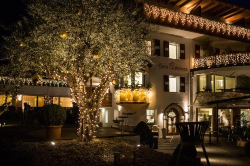 a hotel with christmas lights in front of a tree at Boutique Hotel Zum Rosenbaum in Nalles